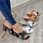 Sandalias de tacón cuadrado Nailin con tiras cruzadas, disponibles en tonos negro, blanco, plata, beige y bronce sobre fondo de madera.