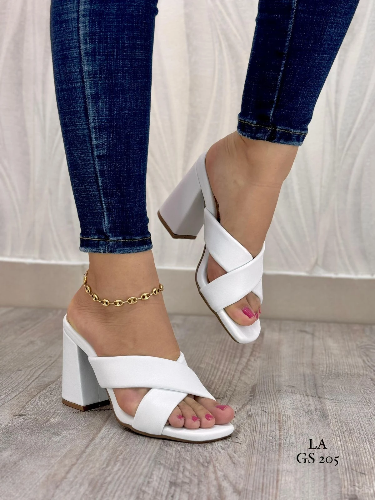 Sandalias de tacón cuadrado blanco con diseño de tiras cruzadas en el empeine, modelo LA GS 205, lucidas con jeans y tobillera dorada.