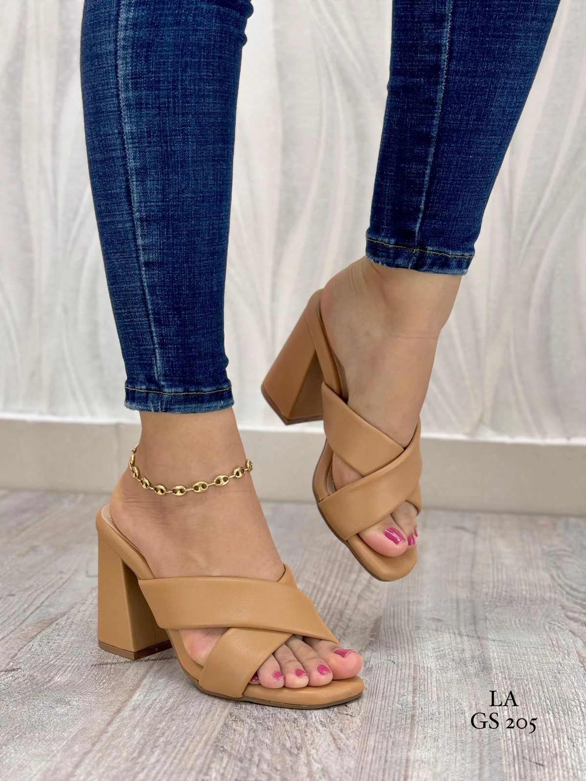 Sandalias de tacón cuadrado color beige con tiras cruzadas en cuero sintético, usadas con jeans, que aportan estabilidad y estilo. Modelo LA GS 205.