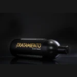 Botella negra de 1000ml de Tratamiento Acondicionador Keracate sobre superficie reflectante con letras doradas, enfocada de lado sobre fondo oscuro.