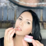 Mujer aplica mascarilla de labios rosa hidratante tipo bálsamo.
