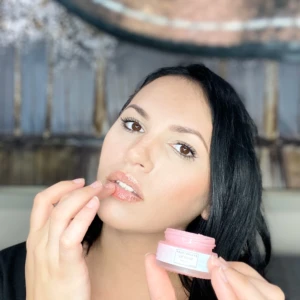 Mujer aplica mascarilla de labios rosa hidratante tipo bálsamo.