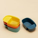 Colador para fregadero de plástico amarillo, naranja y verde apilados; otro azul separado.