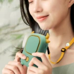 Ventilador de cuello portátil verde con diseño de vaca, colgando del cuello de una persona sonriente.