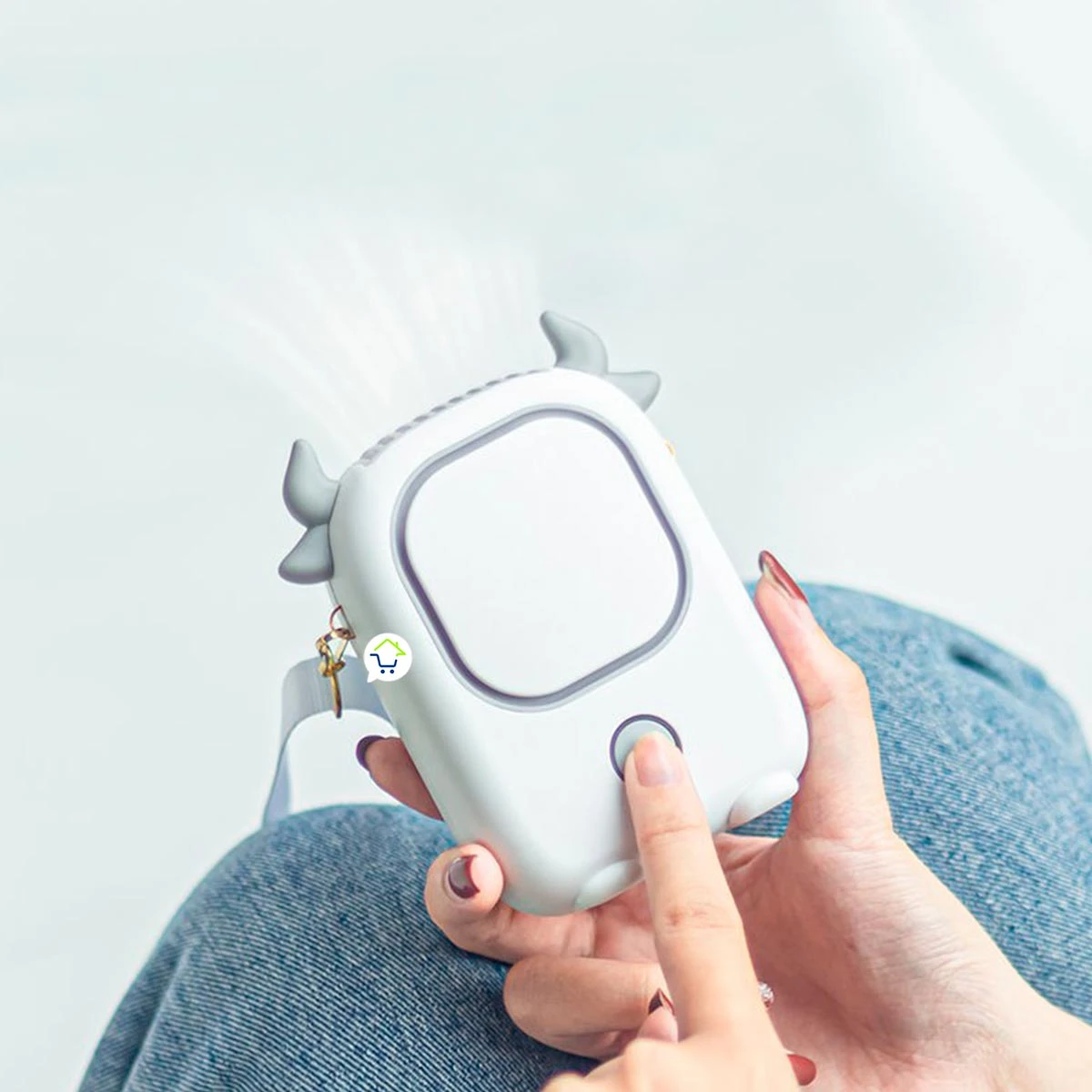 Ventilador de cuello portátil blanco con diseño de vaca, usado por una persona en jeans.