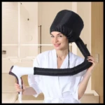 Mujer sonriente usando gorro secador de pelo negro con difusor flexible conectado a secador blanco, en un baño.