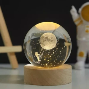 Esfera de cristal con luz LED, astronauta subiendo escalera a la luna, estrellas, base de madera.