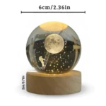 Esfera de cristal con astronauta escalando hacia la luna, sobre base de madera iluminada. Mide 6cm.