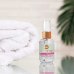 Sérum capilar nutritivo Beauty BE con aceite de argán, moringa y vitamina E en envase transparente, junto a toalla blanca.