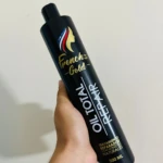 Botella negra de French's Gold Oil Total Repair 500ml con logo de mujer y escudo, sostenida en mano.