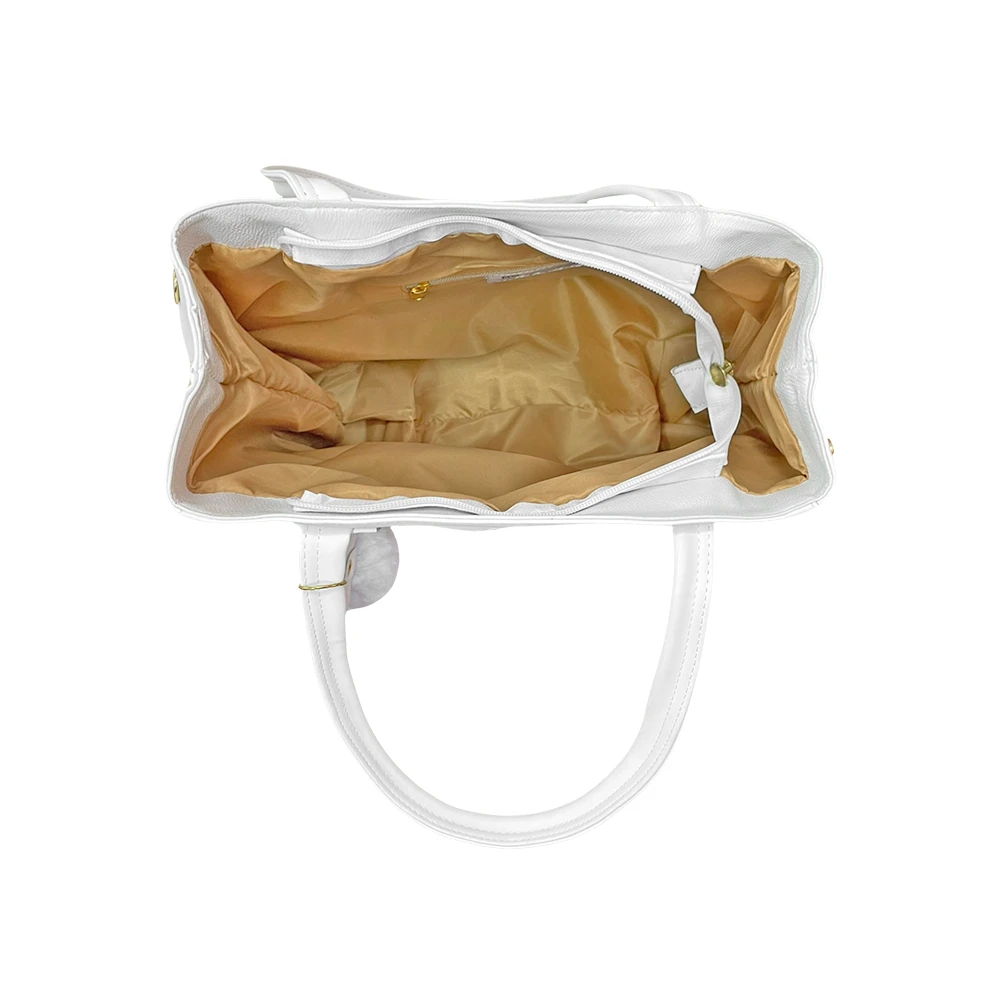 Vista superior de bolso blanco destalonado, mostrando interior forrado en tela dorada y compartimiento con cierre.