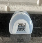 Protector bucal blanco "Bad Boy Pro Series" en estuche plástico translúcido sobre superficie oscura veteada.