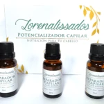Tres frascos de vidrio ámbar con gotas aplicador y tapa negra, etiquetas blancas con letras verdes: "Reparador Capilar Hair Repair" y detalles botánicos dorados.