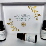Tres frascos ámbar con tratamiento capilar reparador, caja blanca con diseño floral dorado, texto "¡Un cabello increíblemente más hermoso, es posible!".