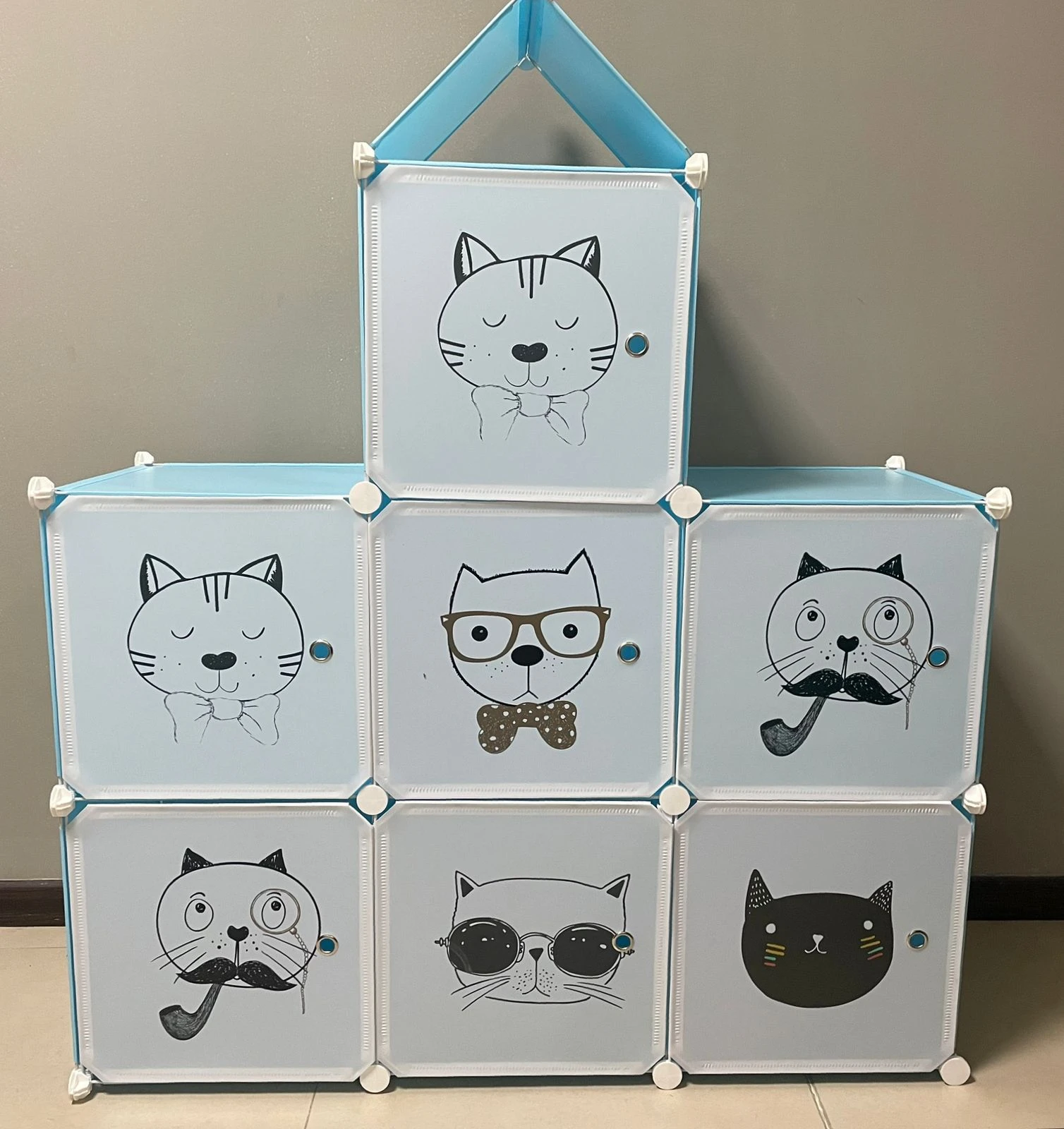Armario organizador azul claro con 7 cubos, cada uno con un diseño de gato diferente, ideal para ropa y juguetes.