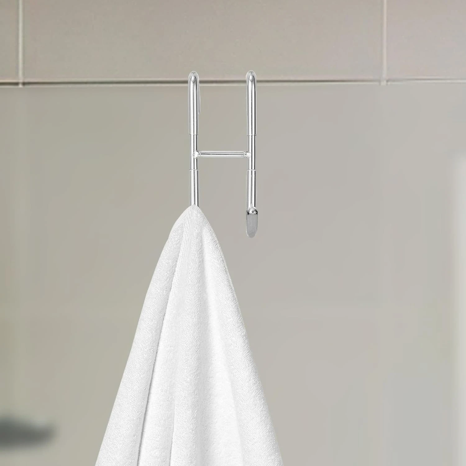 Gancho cromado para puerta, ideal para colgar toallas en baño o cocina.