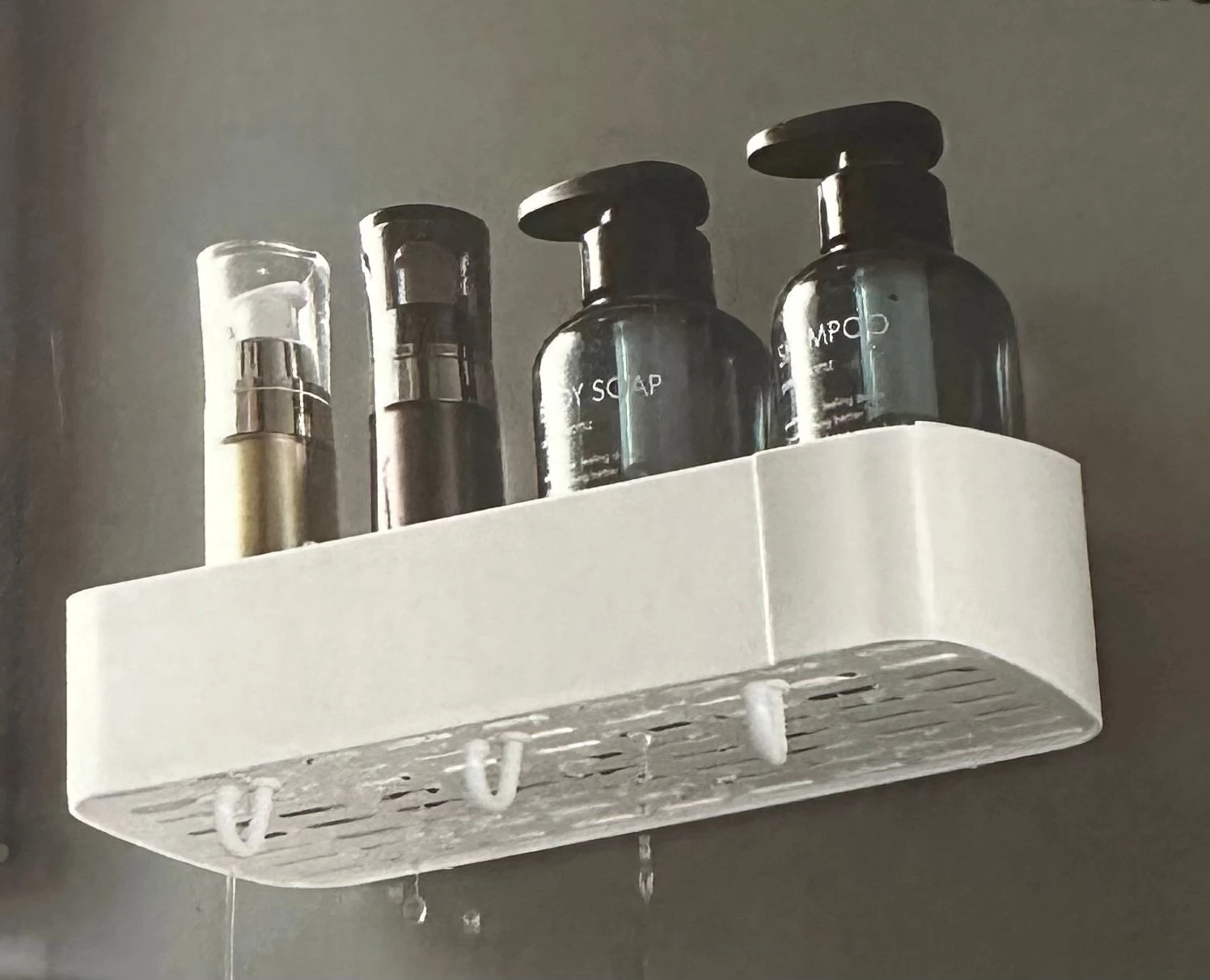 Repisa lineal blanca para baño con dispensadores de jabón y champú, escurre agua.