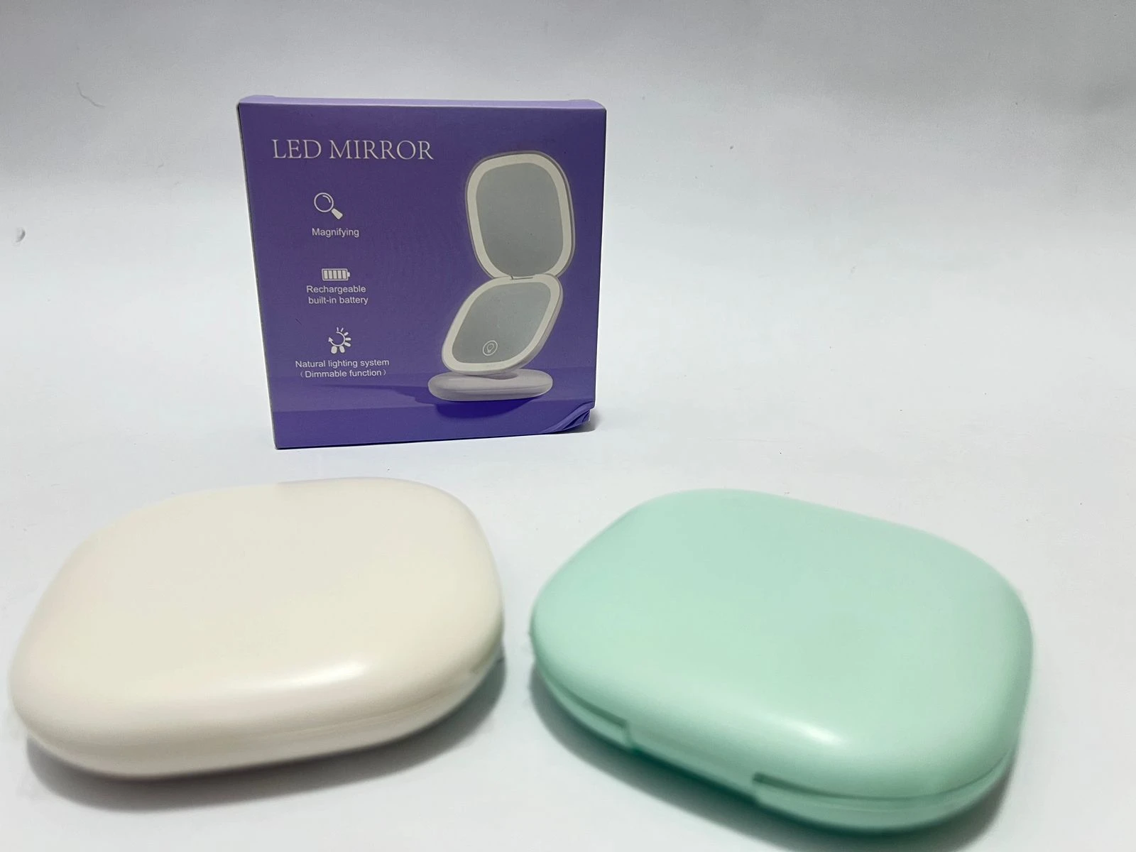 Espejo LED portátil blanco y verde menta, con caja púrpura de descripción "LED Mirror".