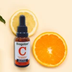 Serum facial Biogotas Vitamina C antiarrugas en frasco ámbar con cuentagotas, acompañado de rodajas de limón y naranja.