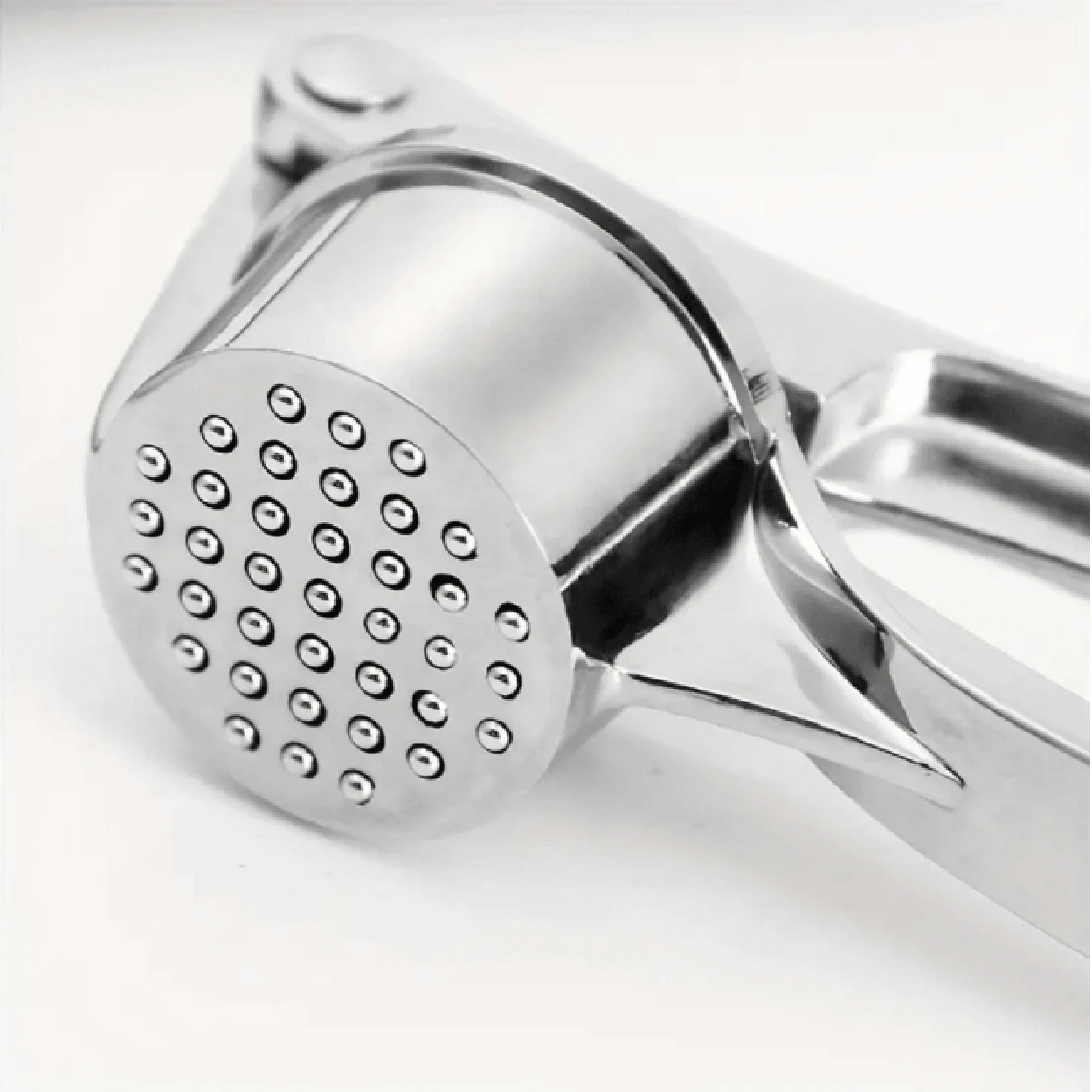 Triturador machacador de ajos metálico plateado con orificios, ideal para cocina.