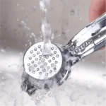 Triturador de ajos metálico bajo chorro de agua, ideal para cocinas modernas.