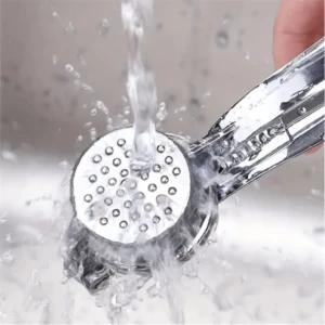 Triturador de ajos metálico bajo chorro de agua, ideal para cocinas modernas.