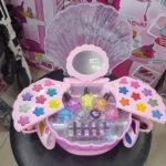 Set de maquillaje infantil en estuche rosa con forma de concha abierta, incluye sombras en forma de estrella, esmaltes, brillos y aplicadores.