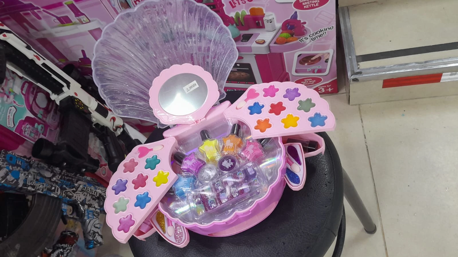 Set de maquillaje infantil con estuche rosa en forma de concha desplegable que incluye variedad de sombras, labiales, esmaltes y aplicadores.