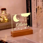 Lámpara LED 3D de acrílico con diseño de luna y nubes, personalizada con el nombre "Olivia" en base de madera.