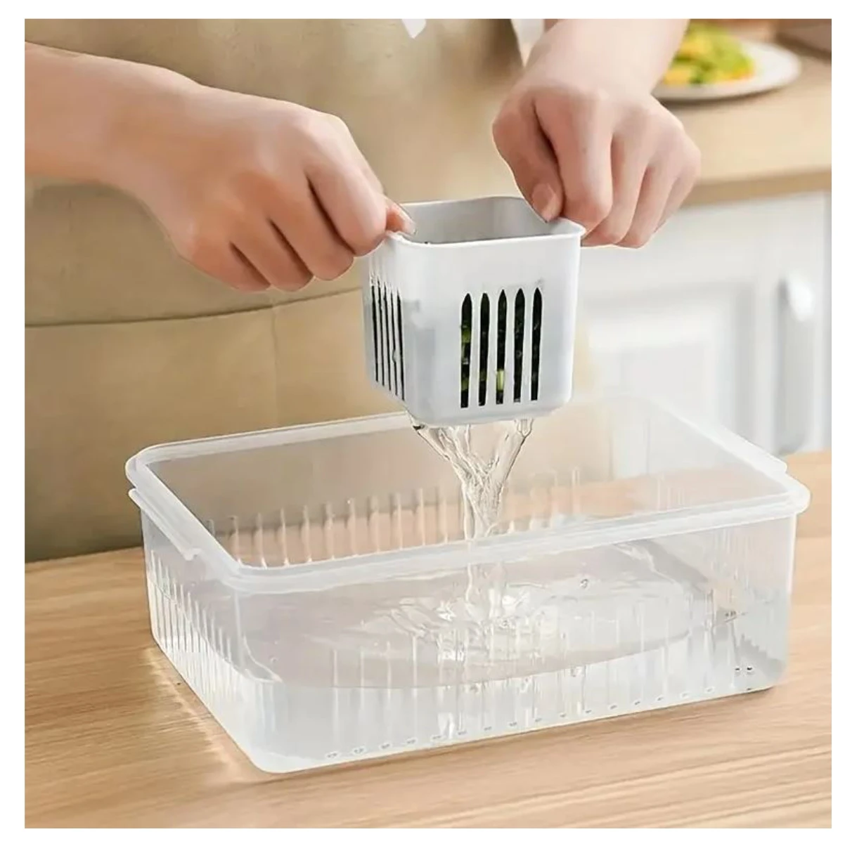 Organizador multipropósito de alimentos con canastilla interna extraíble de plástico blanco, drenando agua sobre el recipiente transparente rectangular.