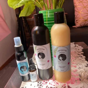 Kit capilar Ana Nikol con shampoo, tratamiento y tónico herbal, presentado en botellas sobre mesa decorada.