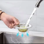 Colador de malla de acero inoxidable para lavaplatos, detiene restos de comida mientras el agua pasa.