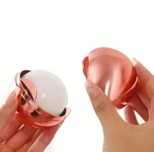 Quita pelusas lavable rosado metálico con aplicador esférico blanco en mano.