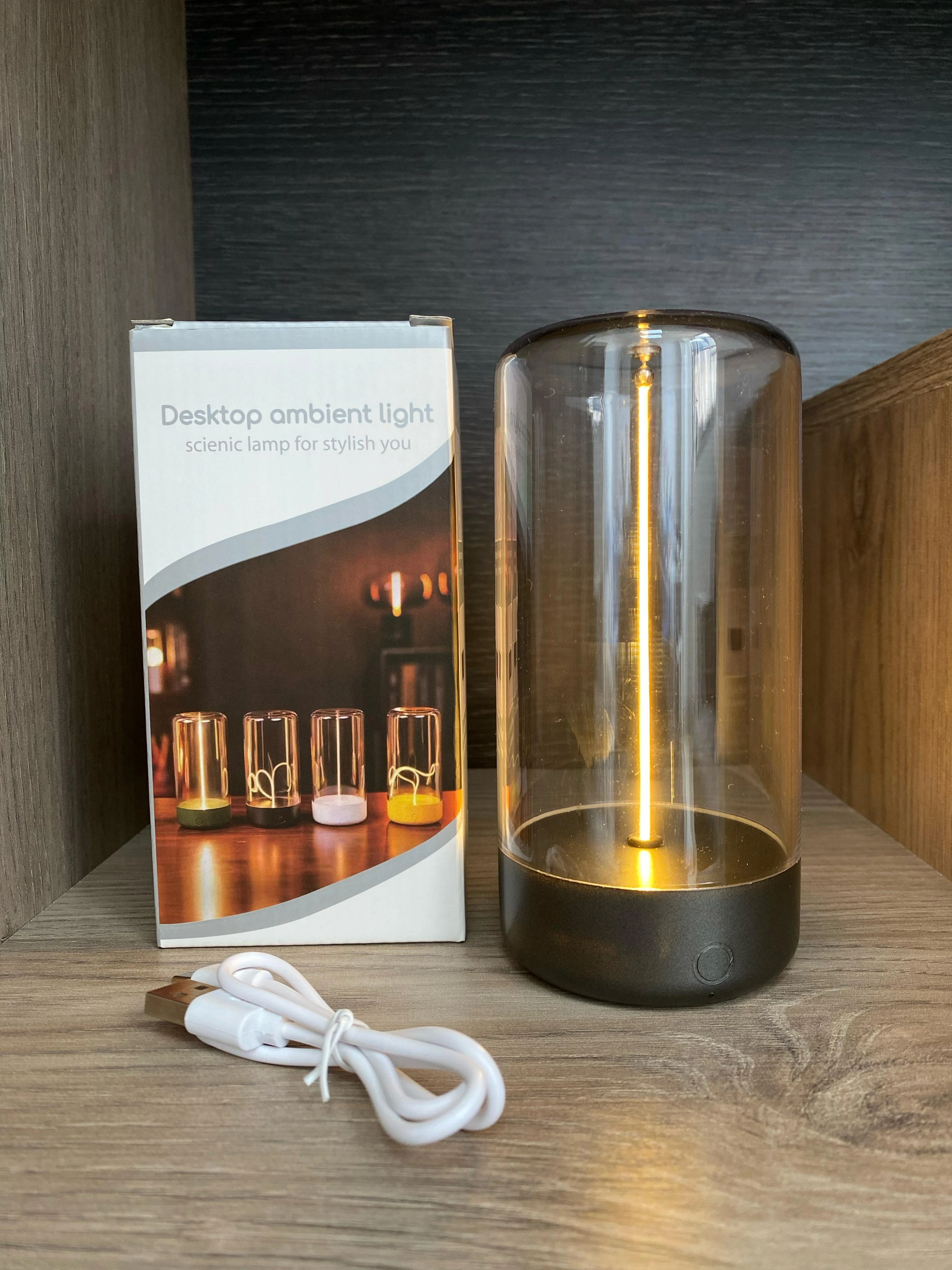 Lámpara táctil imantada de luz cálida con campana de vidrio ahumado, base oscura, cable de carga USB y caja de empaque con diseño de modelos variados.