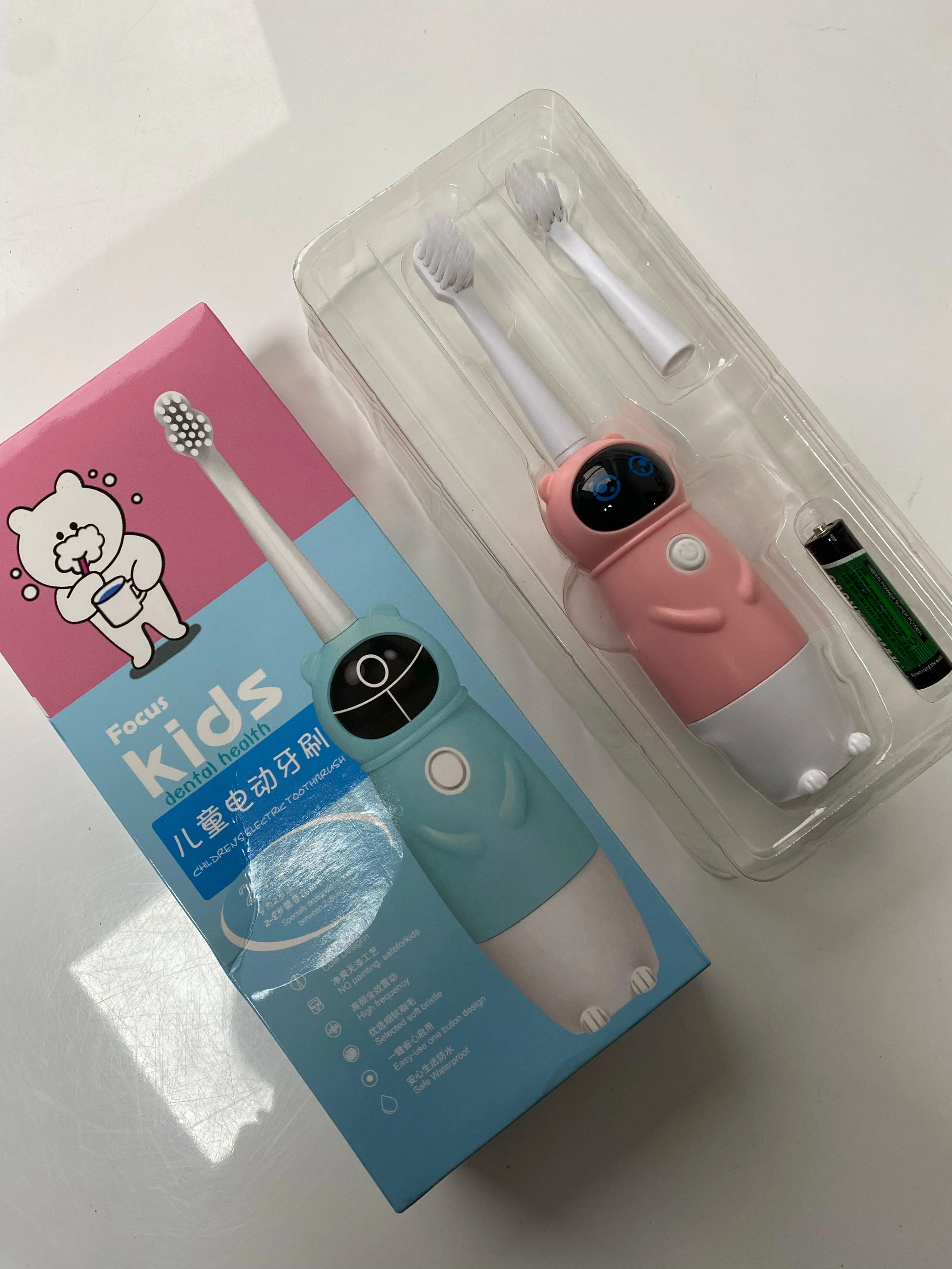 Cepillo de dientes eléctrico infantil rosa y azul con dos repuestos, uno AAA y empaque plástico.