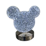 Lámpara LED de mesa con figura de cabeza de ratón en cristal facetado transparente, base metálica plateada brillante.