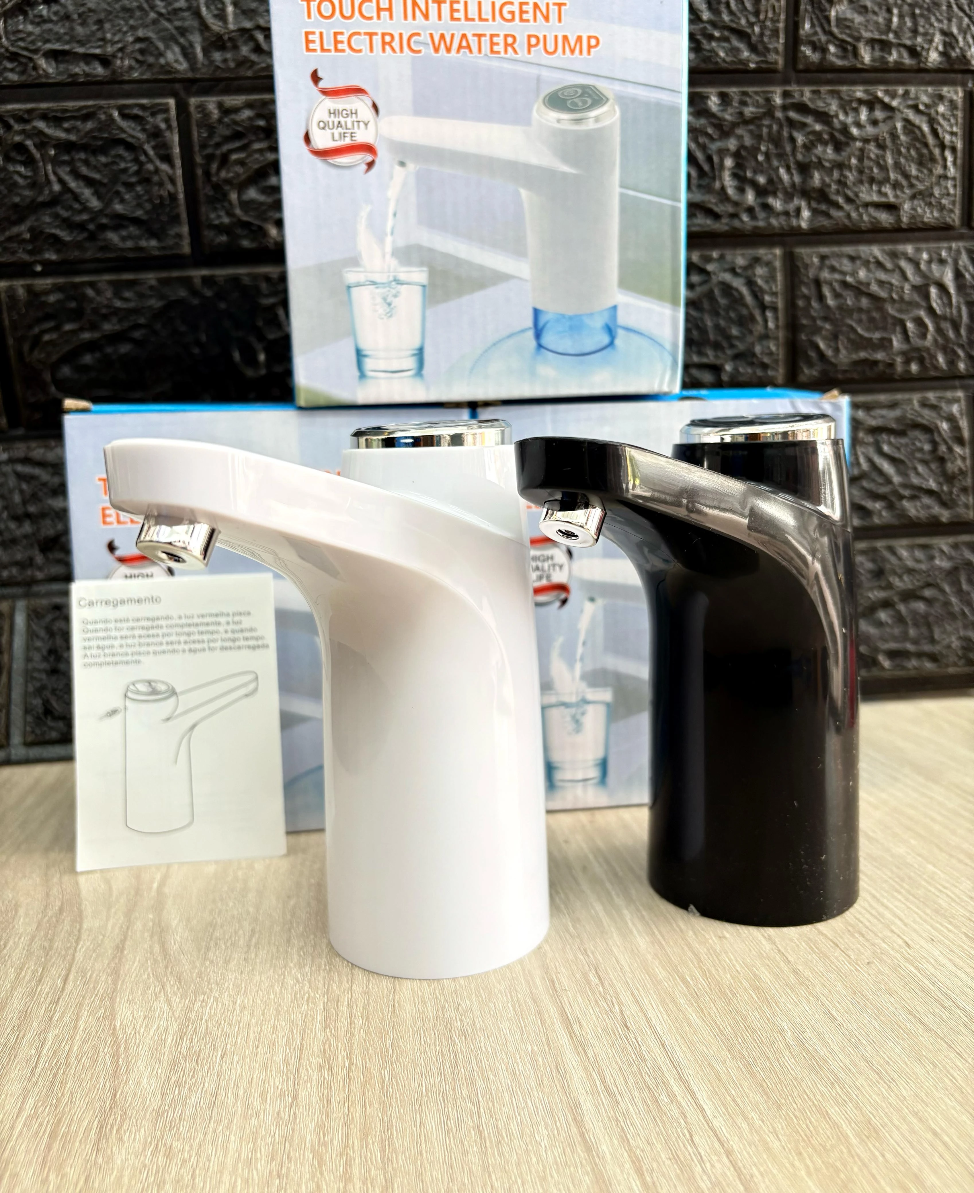 Dispensador eléctrico de agua automático, modelos blanco y negro, sobre superficie de madera clara y fondo de ladrillo oscuro.