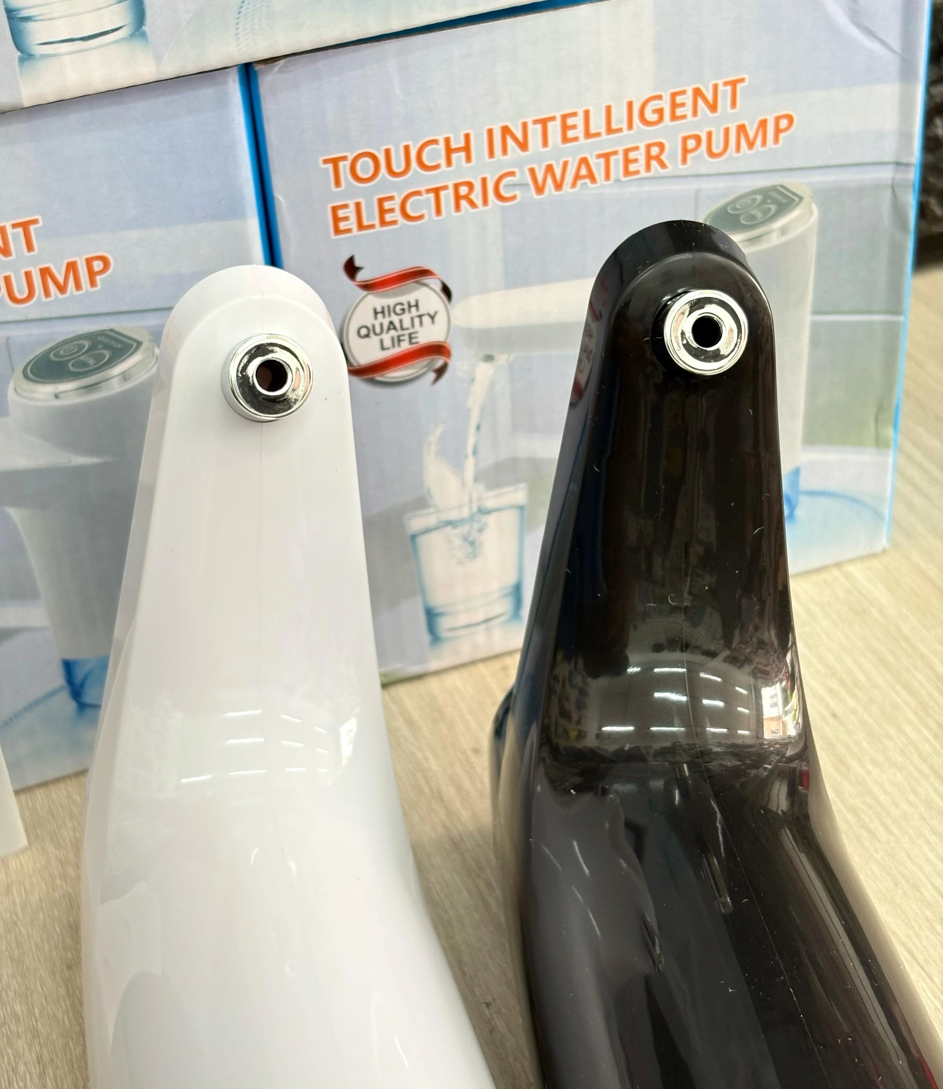 Dispensador de agua eléctrico táctil: boquillas frontal de color blanco y negro. Empaque de fondo.