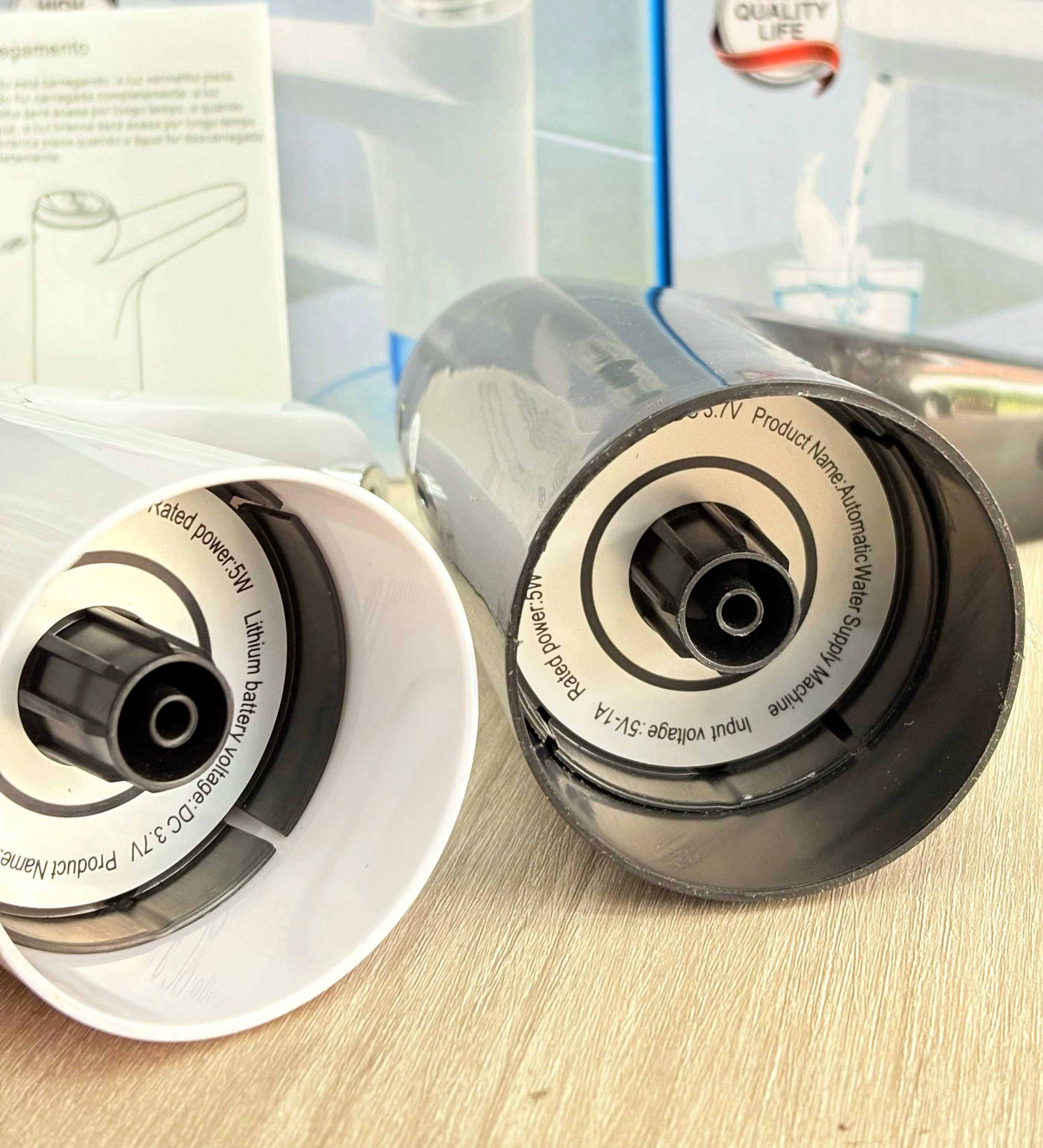 Base de dos dispensadores de agua portátiles, uno blanco y otro negro, mostrando detalles técnicos de voltaje y potencia en sus etiquetas.