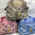 Pañalera cambiador para bebé con diseño de osito y flores en tonos beige, rosa y azul.