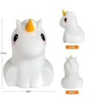 Parlante unicornio de silicona blanca con cuerno amarillo, mide 12.5 cm de alto y 9 cm de ancho, mostrado de frente, de lado y desde la parte posterior.