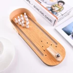 Mini juego de bolos de mesa de madera con bolos blancos, bola metálica y rampa de lanzamiento.