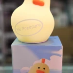 Lampara de noche de silicona con forma de pato amarillo, iluminada, con la frase No Pressure y caja decorativa a juego en la base.