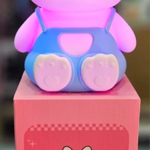 Lámpara de conejo de silicona rosa con luz RGB, porta pañales azules y caja con diseño de conejo.