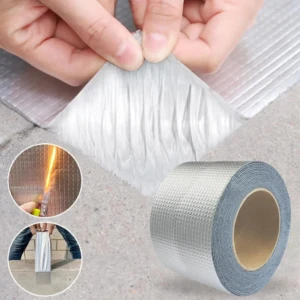 Rollo de cinta selladora impermeable con respaldo de aluminio plateado texturizado, aplicando una sección sobre concreto.
