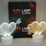 Lámparas decorativas 3D con forma de dos corazones entrelazados, una blanca y otra dorada, con flecha atravesándolas, sobre bases blancas.