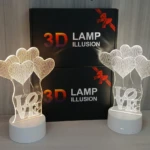 Lámpara decorativa 3D de corazones y palabra "LOVE" con base blanca, ideal para regalo.