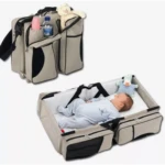 Morral pañalera gris y negro 3 en 1 Asoleado con cambiador portátil y bebé durmiendo.