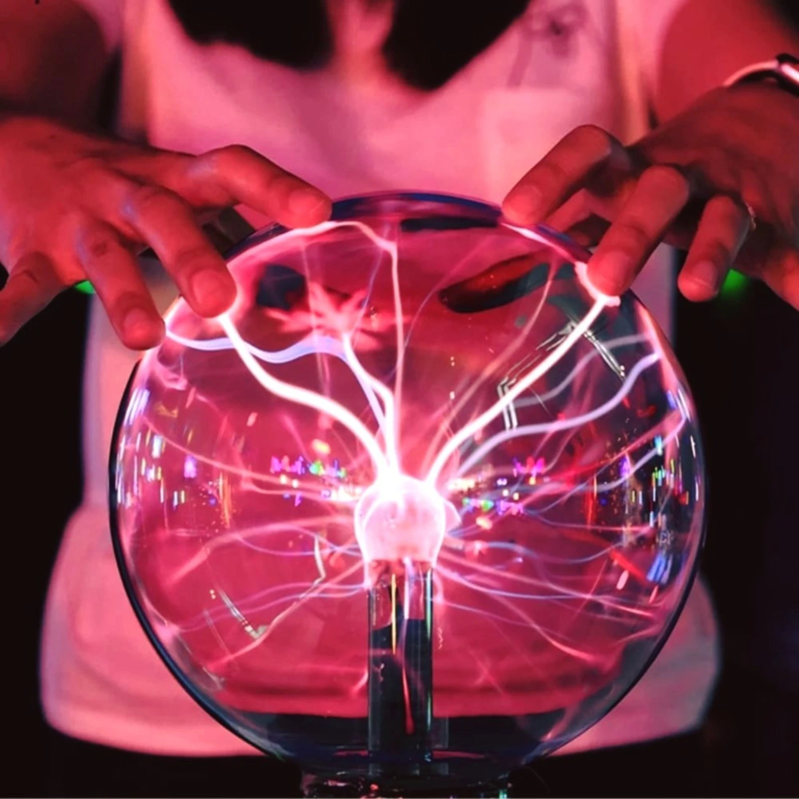 Bola de plasma eléctrica rosa con destellos y dedos humanos interactuando.