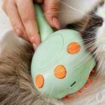 Cepillo vapor para mascotas, color verde, con mango ergonómico y cerdas naranjas de silicona para desenredar el pelaje.